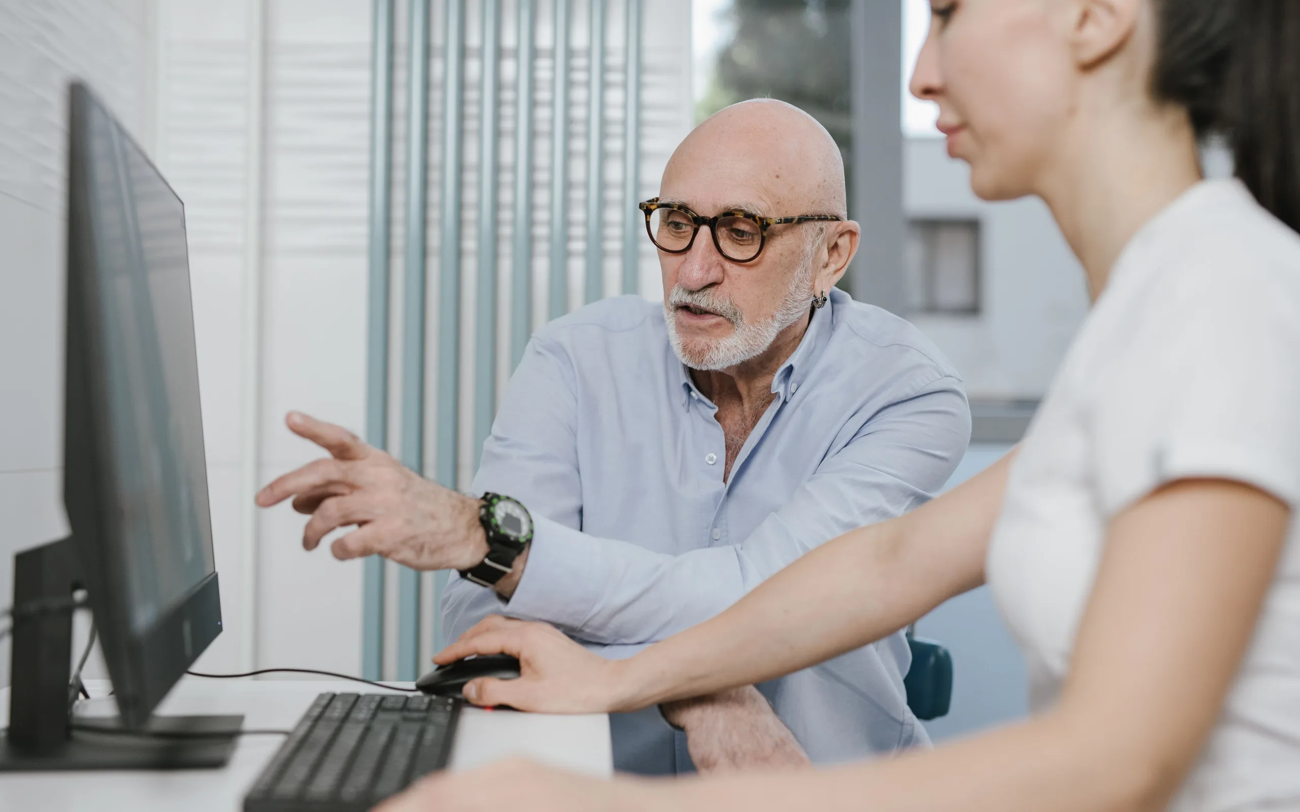 Un mentor montre un écran d’ordinateur à la personne qu’il accompagne, dans un bureau clair
